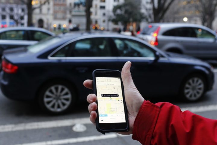2015-03-25 18:57:34 An UBER application is shown as cars drive by in Washington, DC on March 25, 2015. Uber said it was ramping up safety in response to rape allegations against a driver in India and growing concerns about background checks for operators of the popular ride-sharing service. In other cities where Uber operates, critics had complained that a lack of licensing and background checks of drivers could imperil those who use the service. AFP PHOTO/ ANDREW CABALLERO-REYNOLDS