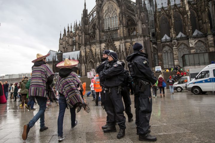 2016-02-08 00:00:00 epa05149546 Police officers stand next to carnival revellers who celebrate despite the rain in Cologne, Germany, 08 February 2016. The carnival's procession for Rose Monday went ahead in Cologne despite the parade in neighboring Duesseldorf being cancelled due to stormy weather. EPA/MAJA HITIJ