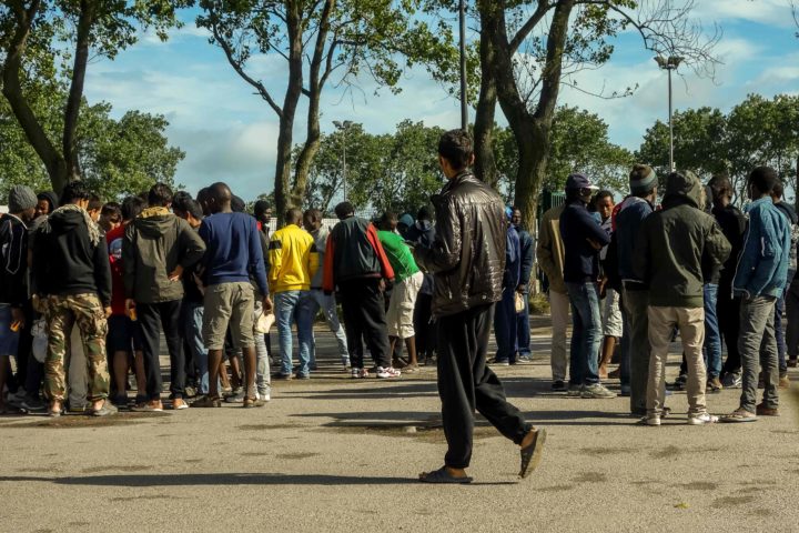2016-08-22 09:46:21 Migrants gather and talk outside the Jules-Ferry aid centre on August 22, 2016 in Calais, next to the so-called "Jungle" migrant camp. / AFP PHOTO / PHILIPPE HUGUEN