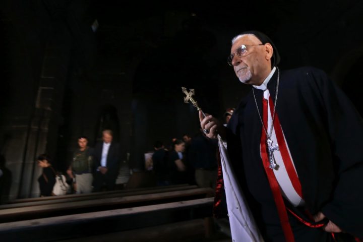 2016-10-30 00:00:00 Archbishop Yohanna Petros Mouche of Mosul prays at the St. George Syriac Catholic Church in the Christian Iraqi town of Bartella, about 15 kilometres (10 miles) east of Mosul on October 30, 2016, after Iraqi forces recaptured it from Islamic State (IS) group jihadists. Iraqi forces are fighting their way toward Mosul to retake it from IS in an operation that is now in its second week, and some Christian villages have already been retaken. / AFP PHOTO / SAFIN HAMED
