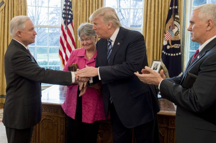 2017-02-09 11:28:11 US President Donald Trump shakes hands with Jeff Sessions (L), alongside his wife Mary (2nd L), after he was sworn in as Attorney General by US Vice President Mike Pence (R) in the Oval Office of the White House in Washington, DC, February 9, 2017. / AFP PHOTO / SAUL LOEB