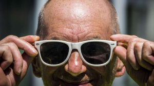 Meneer zet een zonnebril op